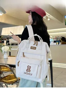 Close-up of white nylon backpack with bear embroidery and fashion text in a cafe