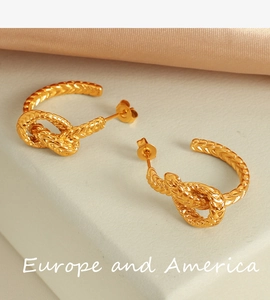 Vue détaillée des boucles d'oreilles serpent dorées avec texture d'écailles gravées