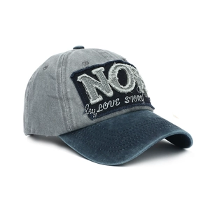 Detail of distressed grey baseball cap with navy brim and embroidered 'NO' patch