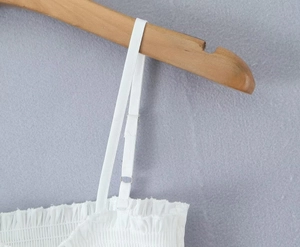 Détail des bretelles réglables et texture froncée sur un haut blanc pour femmes