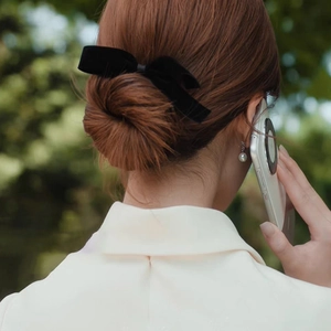 Elegant black velvet bow hair clip worn on a bun hairstyle for a sophisticated look