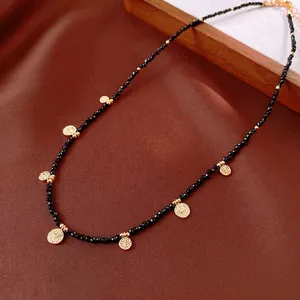 Vintage round black crystal beaded necklace with golden dotted charms on brown fabric