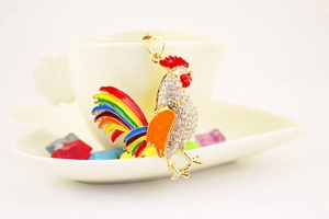Close-up of rooster keychain with colorful enamel feathers and sparkling rhinestones
