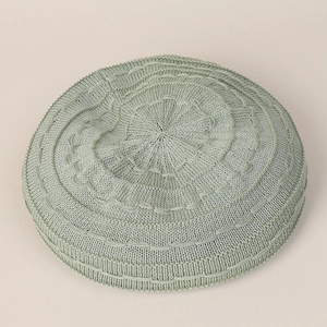 Top down close-up of light green knitted beret showing intricate texture and crown pattern