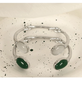 Detail of silver-finish irregular cuff bracelet featuring green and white cat eye stones