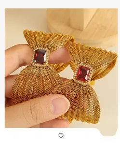 Close-up of golden woven bow bracelets with large red rubies and diamond accents