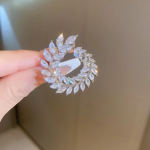 Detailed view of a silver leaf brooch with marquise-cut white zircons held in hand