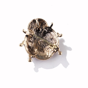 Makroaufnahme der Marienkäfer-Brosche in Vintage-Gold mit Metalltextur und Nadelverschluss