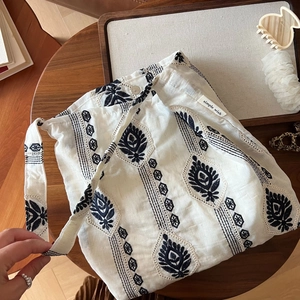 Détail du sac à bandoulière en lin vintage avec broderie florale sur surface en bois rustique