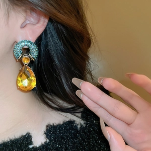 Vintage palace style drop earrings with amber crystal and teal rhinestones on a model