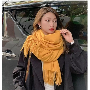 Macro shot of bright yellow cashmere-like scarf texture and long fringe tassels