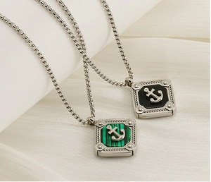 Macro detail of nautical anchor pendants with black enamel and green malachite inlays