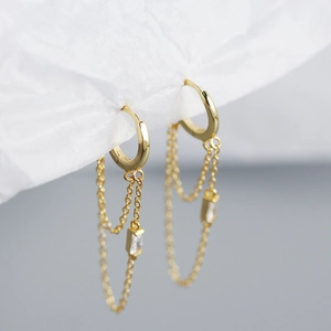 Macro shot of gold double chain tassel earrings with rectangular cubic zirconia pendants