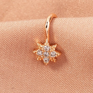 Macro shot of rose gold star-shaped faux nose ring with inlaid zircon on champagne silk