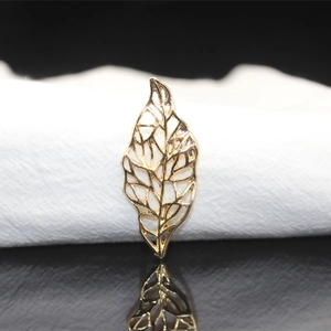 Macro detail of golden filigree hollow leaf accessory for handmade bridal jewelry craft