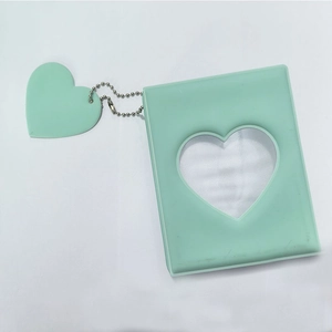 Detail of mint green mini photo album with heart-shaped cutout and matching charm