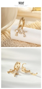 Detail showing gold cross huggie earrings with white zircon inlay on white props