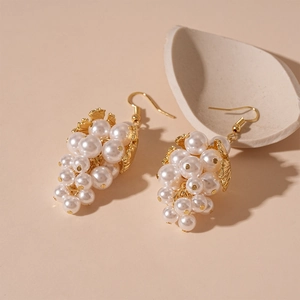 Detailed view of grape cluster earrings with white pearls and golden leaf accents
