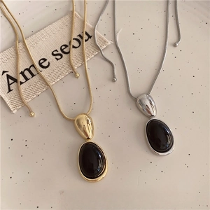 Macro view of gold and silver snake chain necklaces with oval black resin pendants