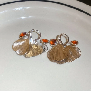 Detail of gold petal fan earrings with amber crystals and brushed metal texture