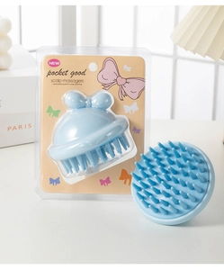 Macro shot of blue scalp massager with removable silicone bristles and retail packaging