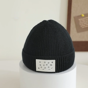 Close-up of black ribbed knit beanie with stylish letter patch on a modern display