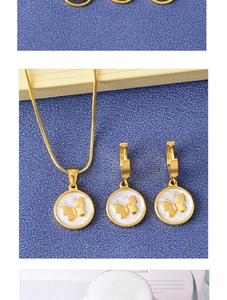 Detailed close-up of golden butterfly pendant and earrings set on a textured blue surface