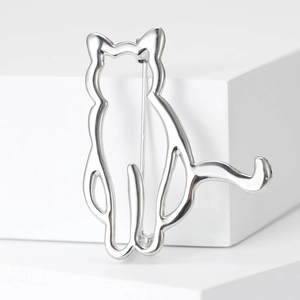 Minimalist silver cat-shaped alloy brooch displayed on white geometric studio props