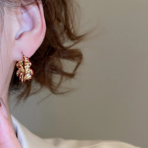 Close-up of gold and red petal earring with enamel detail on model's ear