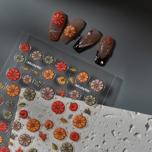 3D Halloween nail art stickers with pumpkin and maple leaf patterns on a grey background