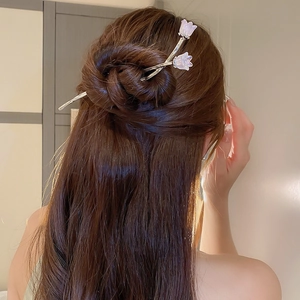 Vue détaillée du pic à cheveux argenté avec fleurs de tulipes violettes dans un chignon
