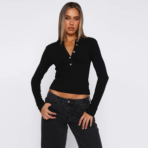 Close-up of black ribbed long-sleeve top featuring functional white button placket detail