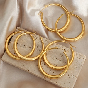 Three pairs of polished gold hoop earrings in small medium and large sizes on stone