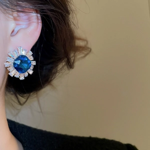 Detail of sunflower ear stud featuring deep blue gemstone and sparkling zircon accents