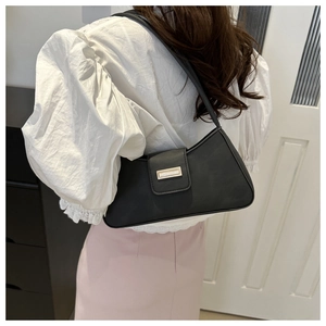 Detail showing back view of black baguette shoulder bag with golden metal buckle on model