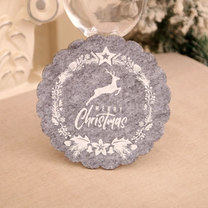 Detail of grey felt Christmas coaster with white reindeer wreath on a beige cloth