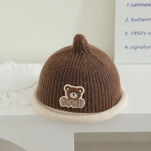 Detail of warm knitted baby hat with bear embroidery and white rolled brim