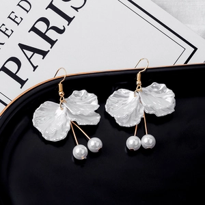Elegant white petal drop earrings with gold hooks and pearl accents on a tray