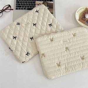 Detailed close-up of quilted laptop sleeve with bow and cute rabbit embroidery