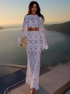 Elegant white lace two-piece set featuring long sleeve crop top and maxi skirt on coastal sunset