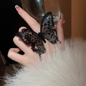Macro shot of oversized black translucent acrylic butterfly ring with silver glitter detail