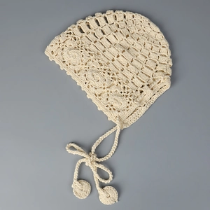 Détail du bonnet de bébé au crochet avec maille ajourée et bordure en dentelle fleurie