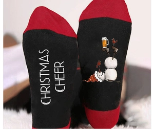 Close-up of red and black Christmas socks with snowman graphics and holiday slogans