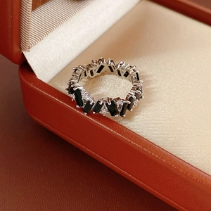 Macro shot of silver ring with black rectangular stones and white zircons in a gift box