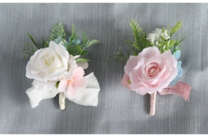 Close-up of white and pink faux roses wedding corsages with ribbon wrapped stems