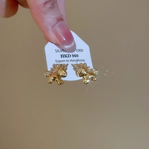 Close-up of golden unicorn earrings made of S1000 silver with sparkling crystals