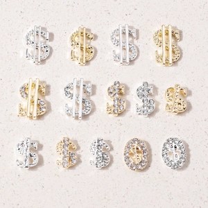 Macro detail of gold and silver dollar sign nail charms with shimmering rhinestones
