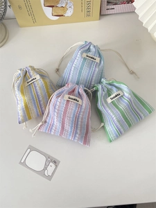 Detailed close-up of striped drawstring storage bags in yellow, blue, pink and green tones
