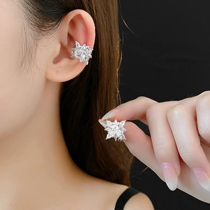 Close-up of silver snowflake ear bone clip with sparkling zircons worn on the ear