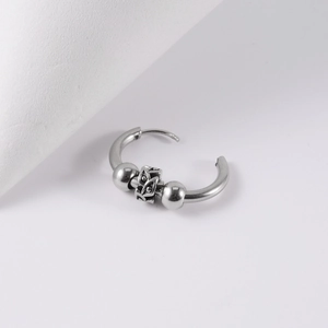 Close-up of gothic stainless steel hoop earring with engraved beads and punk details